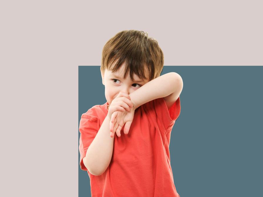 Foto af dreng, der er genert og holder sine hænder op foran hovedet